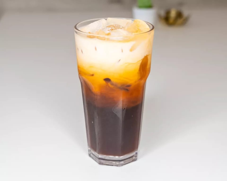 Iced Thai tea with distinct layers of dark tea and creamy milk, topped with ice.