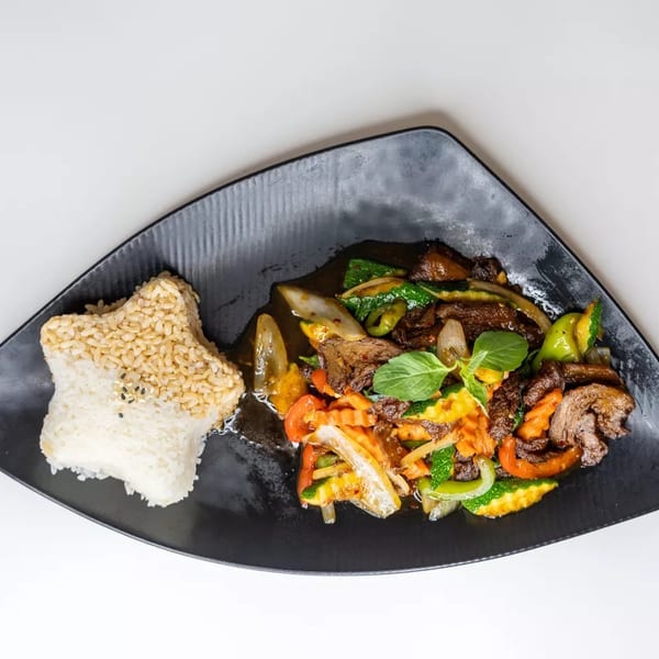 Star-shaped rice with sesame seeds next to a colorful stir-fry with meat and vegetables.
