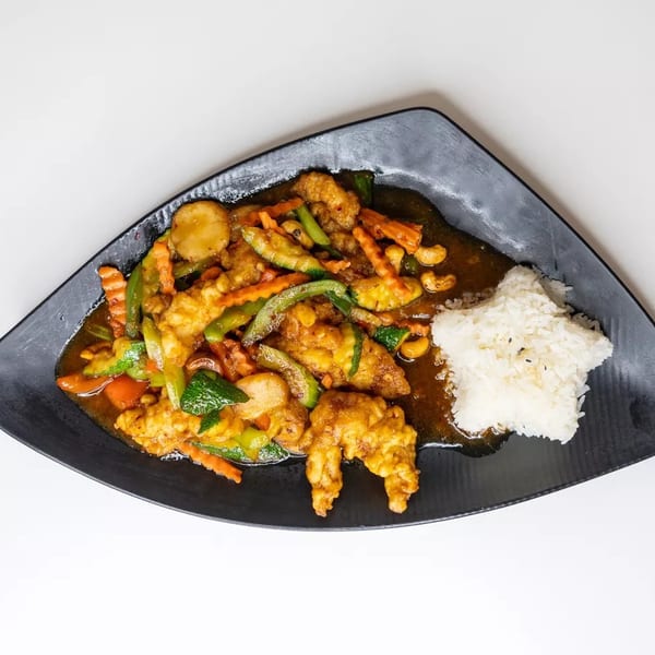 Sweet and sour chicken with mixed vegetables and star-shaped rice on a black plate.