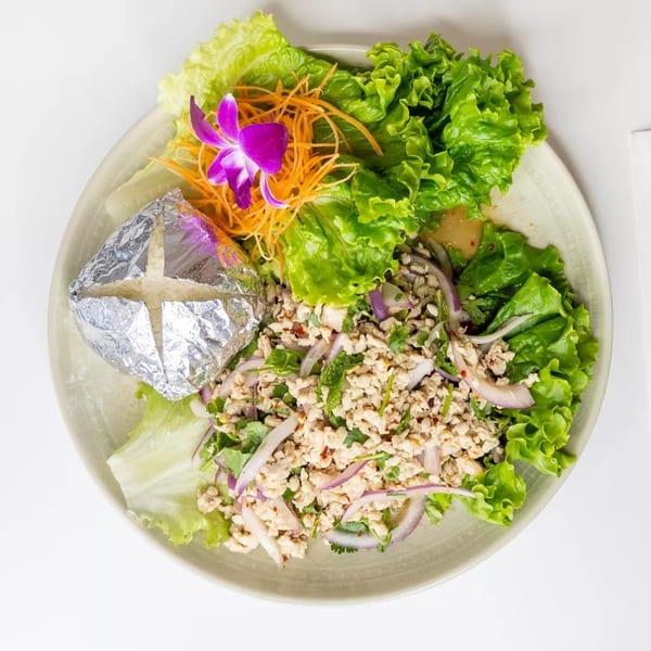 Larb Gai, a Thai chicken salad with lettuce, red onion, and herbs, served with sticky rice.